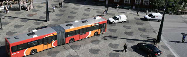 Foto som visar trafiksituation med bussar, bilar och människor.