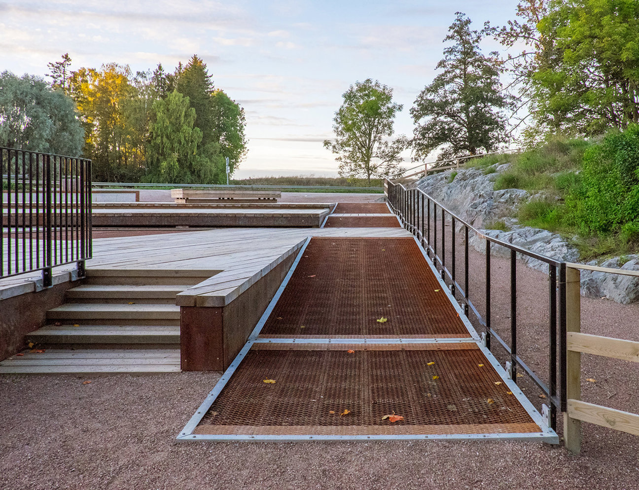 En ramp med metallgaller, trappor, räcken och träd i bakgrunden.