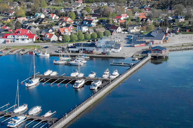 Flygfoto av en hamn med båtar, bryggor och hus vid vattnet.