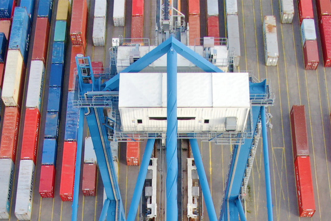 Färgglada containrar och en blå kran på en containerhamn.