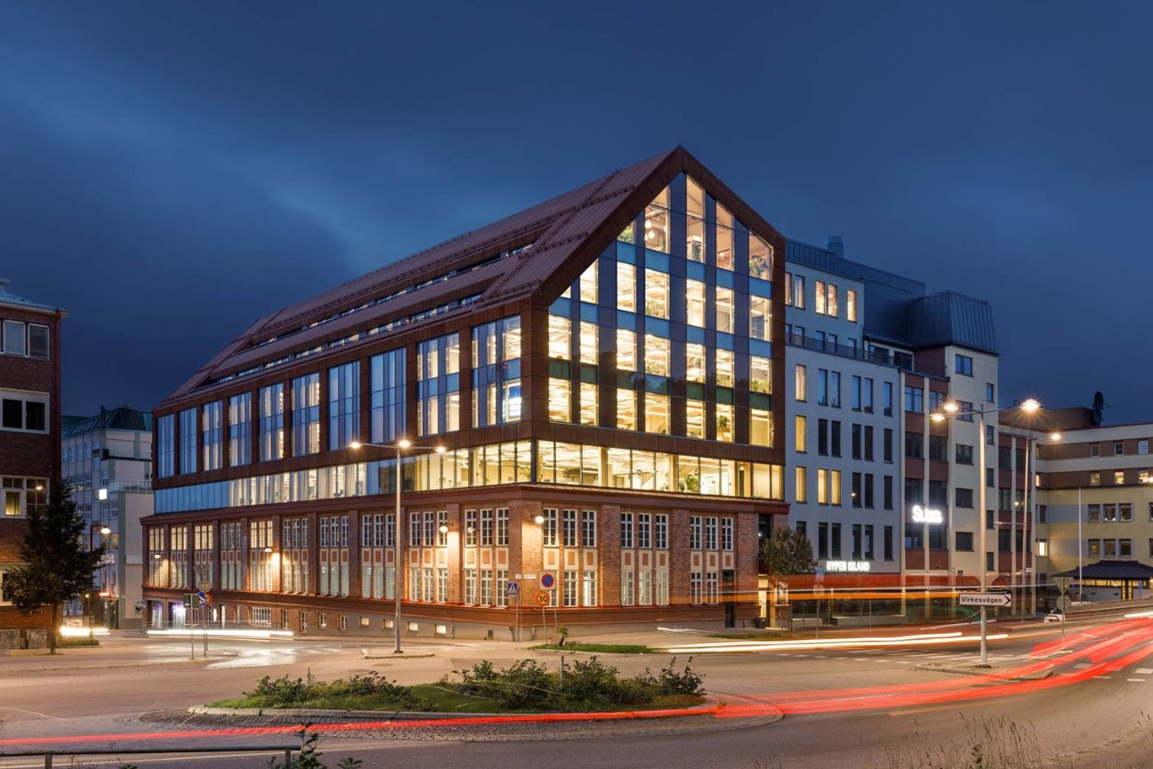 Byggnad med glasfasad och tegelväggar vid kvällstid.