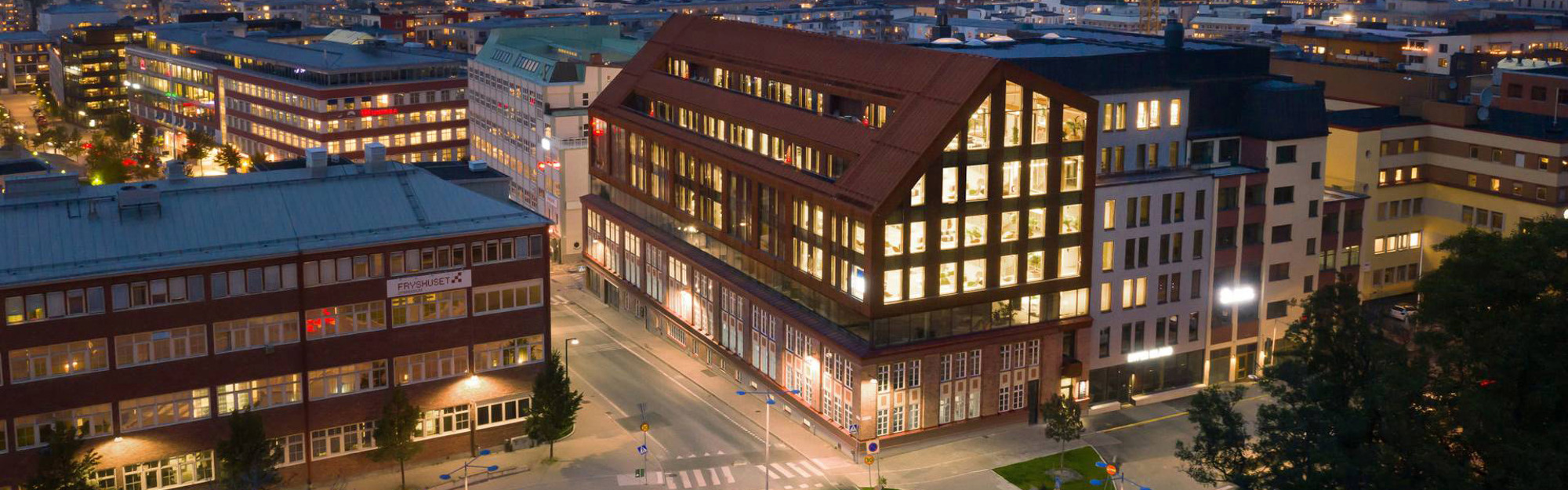 Nattvy över stadsbyggnader med belysta fönster och tomma gator.