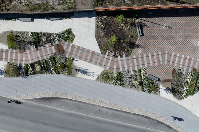 Luftbild av en utomhusplats med mönstrade stigbanor, växter och en väg.