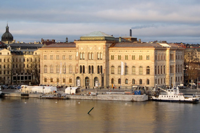 Nationalmuseum byggnad vid vatten med båt och andra byggnader i bakgrunden.