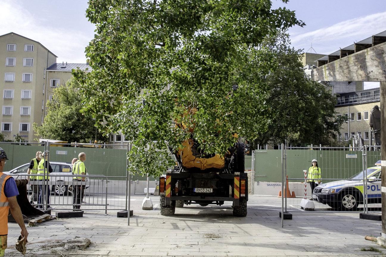 Byggarbetsplats med kran, arbetare i reflexvästar och polisbil.