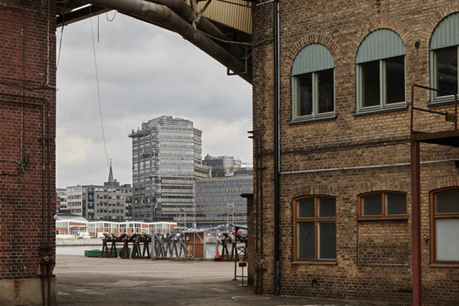 Tegelbyggnader med båge och stadslandskap i bakgrunden under molnigt väder.